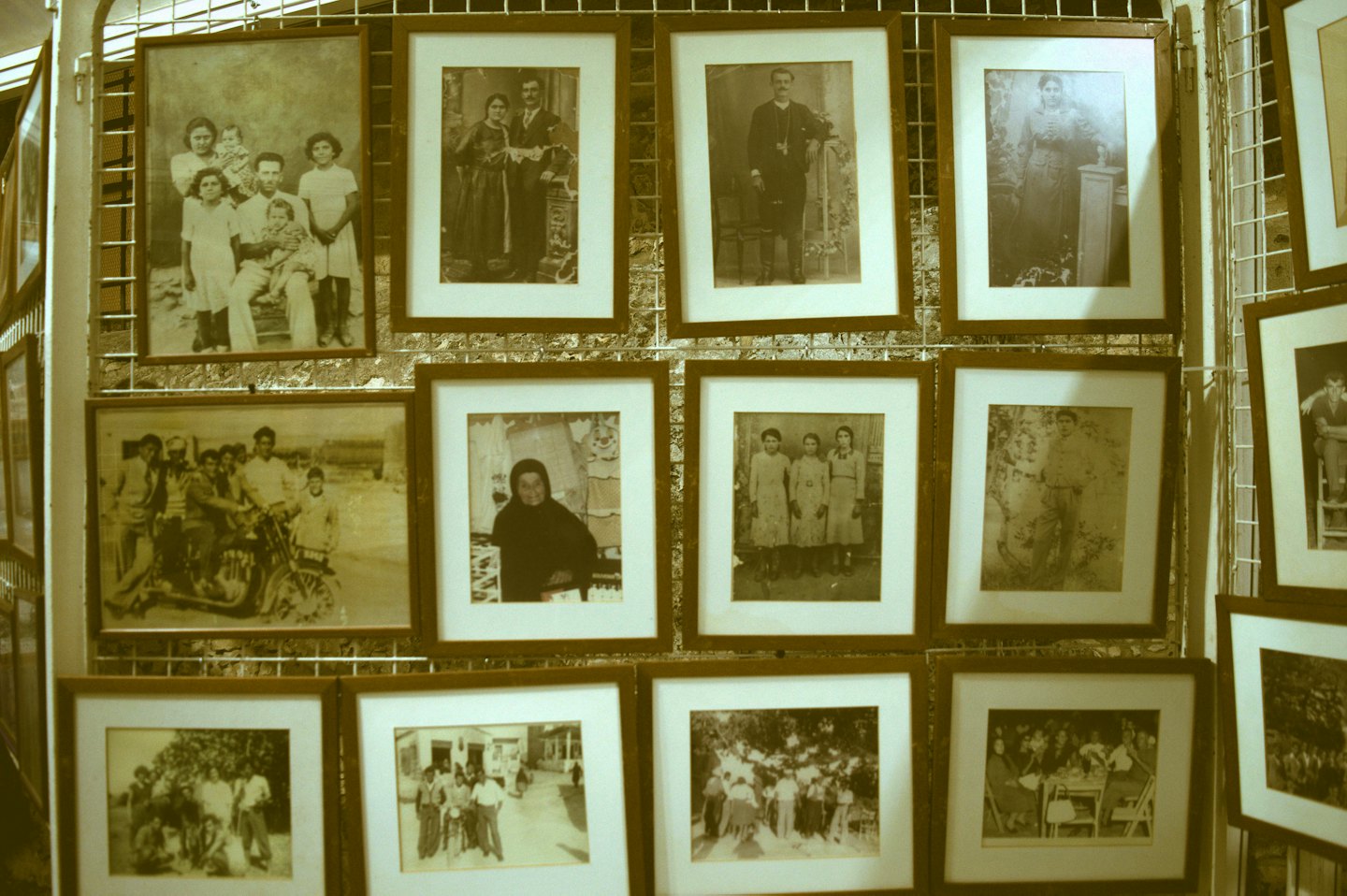 Ritratti di famiglia vintage esposti su una parete a griglia bianca.