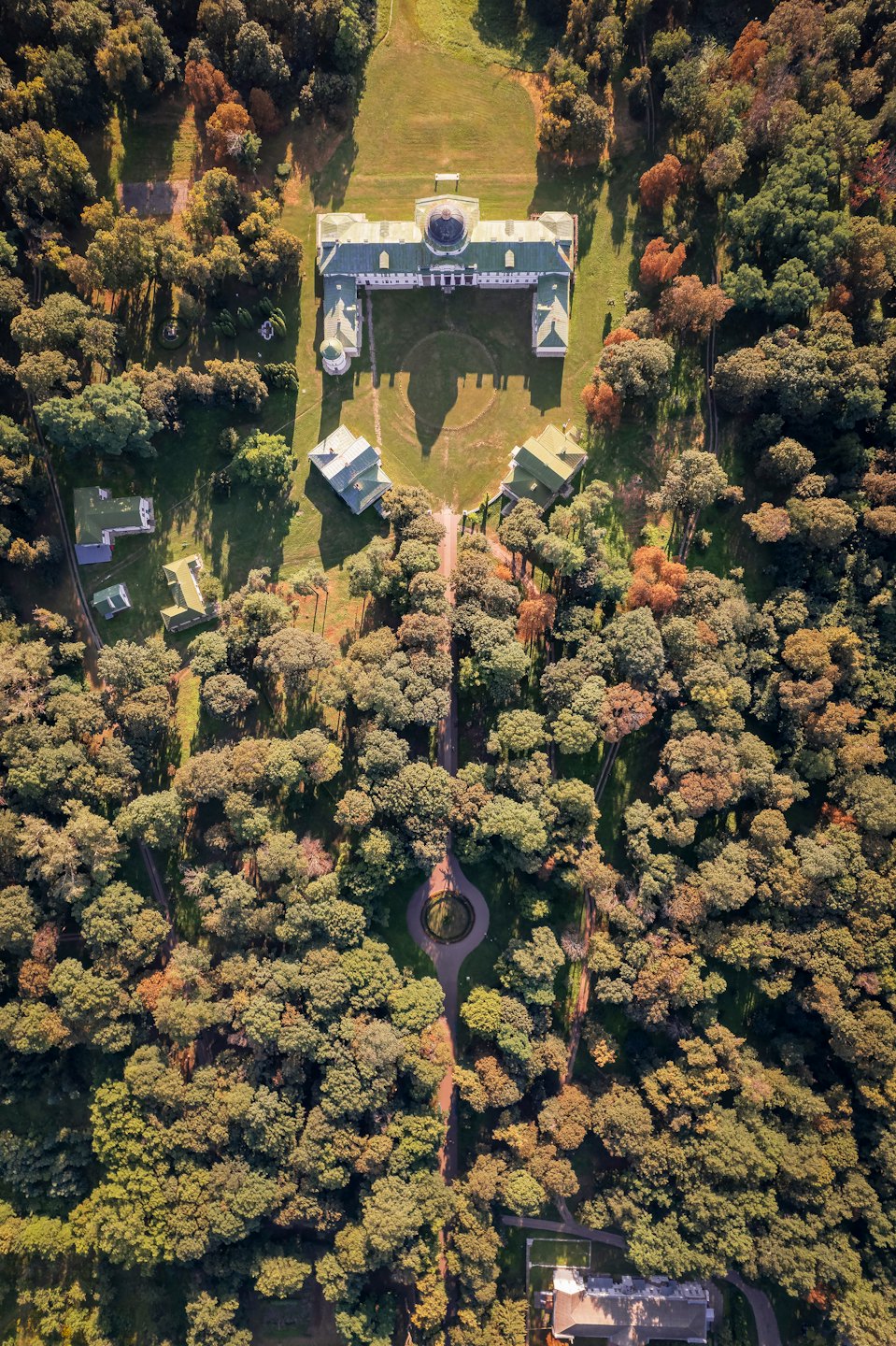 Grande villa bianca con tetti verdi circondata dal fogliame autunnale.