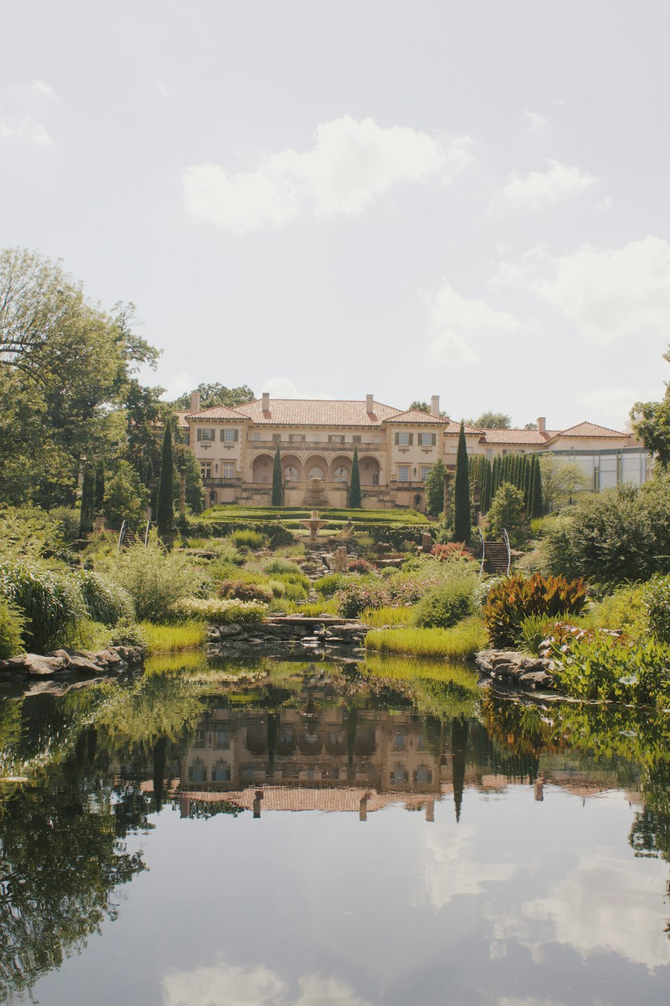 Grande villa in stile italiano con giardini curati si riflette in uno stagno.